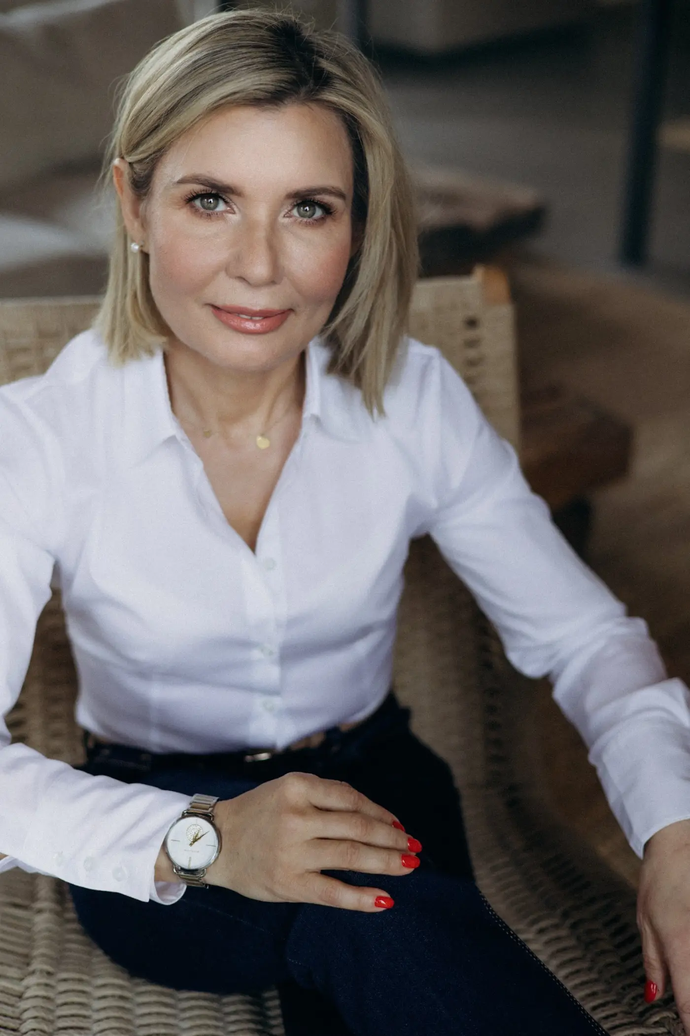 Portret Ewy Pędzich-Ościłowskiej w biurze Ewa Pędzich-Ościłowska siedzi w fotelu w jasnej koszuli.